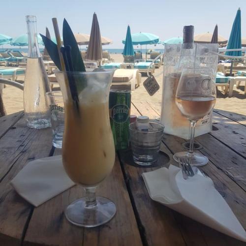- une table en bois avec une boisson et des verres sur la plage dans l'établissement Joli petit pavillon climatisé 50 m de la mer, à Saint Pierre La Mer