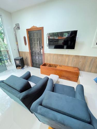 a living room with two blue couches and a tv at Cabanas Cantareira - Araucária in Mairiporã