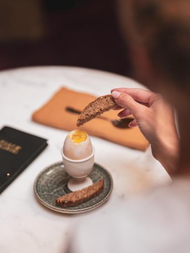 a person holding a piece of food on a table at Boudoir des Muses in Paris