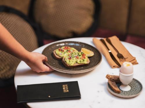 a person holding a plate of food on a table at Boudoir des Muses in Paris