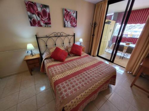 a bedroom with a bed with red pillows on it at Olivia Sunset 31 - One Bed in Puerto de Santiago