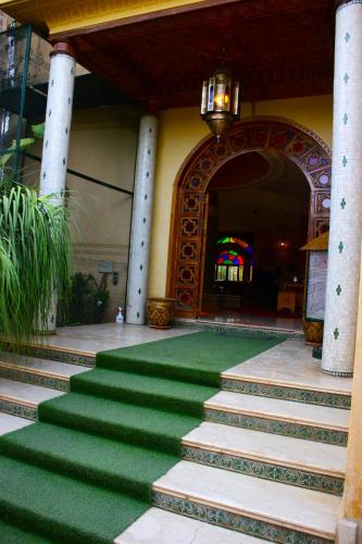 a building with a green carpet in front of a building at Riad Noumidya in Fès