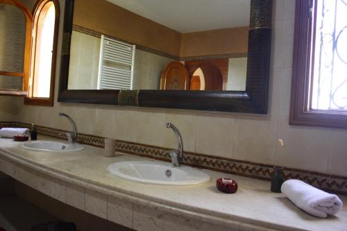 a bathroom with two sinks and a large mirror at Riad Noumidya in Fès