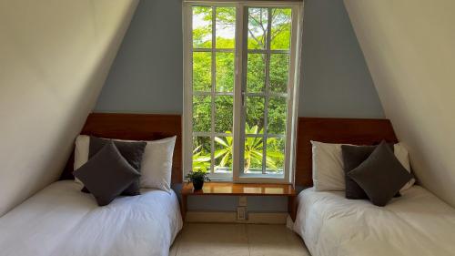two beds in a room with a window at VILLAS EL ENCANTO in Jalpan