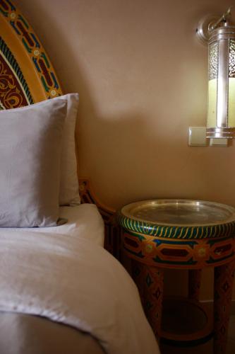 a bedroom with a bed and a table with a lamp at Riad Noumidya in Fès