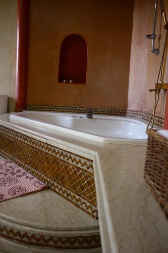 a large bath tub in a bathroom with a tile floor at Riad Noumidya in Fès