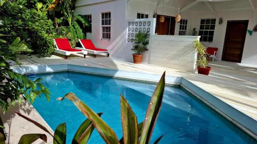 a swimming pool in a yard with red chairs at Amanda's Place Casa Amancer - sea view, pool and tropical garden in Caye Caulker