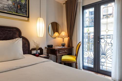una camera da letto con un letto e una scrivania con una finestra di Calista Trendy Hotel & Spa a Hanoi