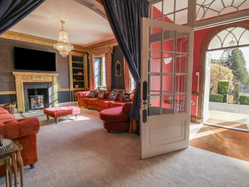 a living room with red furniture and a glass door at Llwynderw Hall in Llanwrtyd Wells