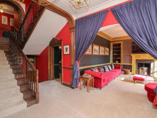 a living room with a red couch and a staircase at Llwynderw Hall in Llanwrtyd Wells