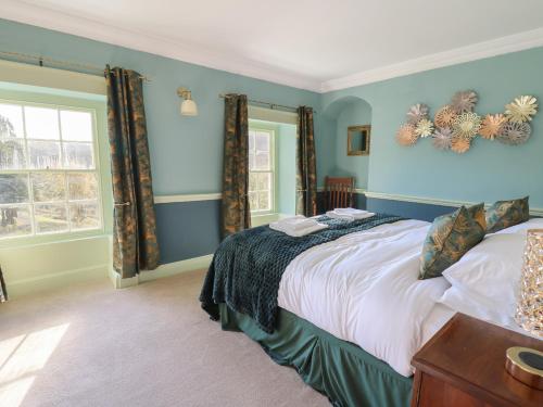 a bedroom with a bed with blue walls and a window at Llwynderw Hall in Llanwrtyd Wells