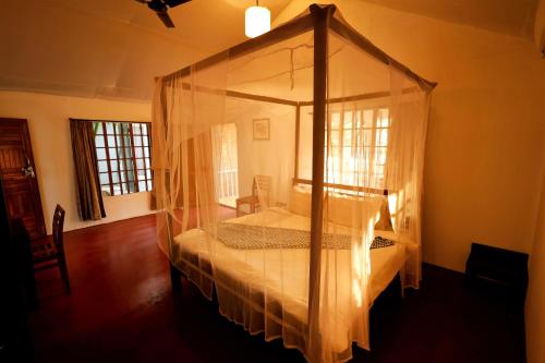 a bedroom with a canopy bed in a room at Temple Garden Palolem in Canacona