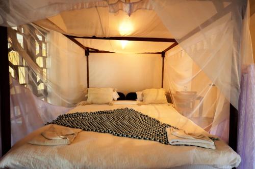 a bedroom with a canopy bed with white curtains at Temple Garden Palolem in Canacona
