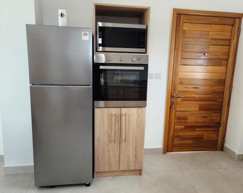 a kitchen with a stainless steel refrigerator and a microwave at Luxury Seaview Apartment Flic en Flac CFF07 in Flic-en-Flac