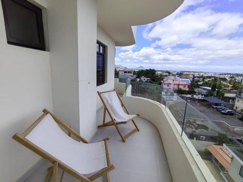 a balcony with two chairs and a view of a city at Luxury Seaview Apartment Flic en Flac CFF07 in Flic-en-Flac