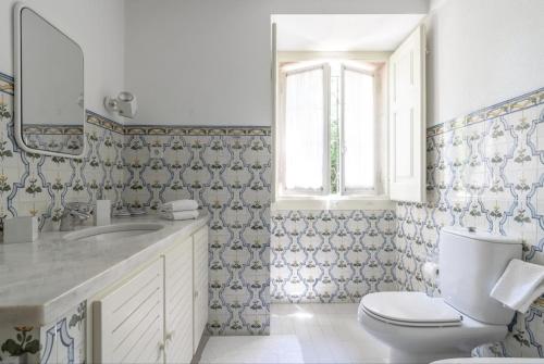 ein Badezimmer mit Toilette, Waschbecken und Spiegel in der Unterkunft Quinta da Penalva - Sintra in Sintra