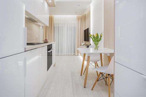 a kitchen with white cabinets and a table with flowers at MIA Centrum Wrocław in Wrocław