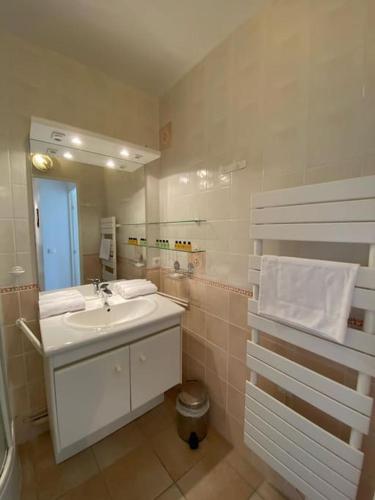 une salle de bain blanche avec un lavabo et un miroir dans l'établissement Charmant appartement en bord de mer, à Cabourg