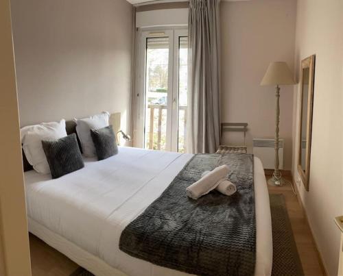 une chambre avec un grand lit blanc avec une fenêtre dans l'établissement Charmant appartement en bord de mer, à Cabourg