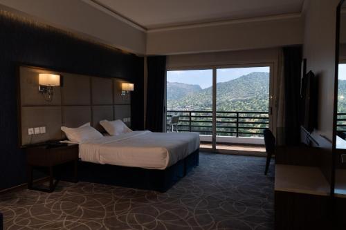 a hotel room with a bed and a large window at فندق إكليل الجبل in Ash Shafa