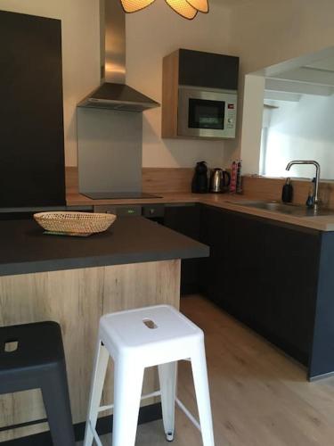 une cuisine avec un comptoir et un tabouret blanc dans l'établissement Maison familiale dans les pins à 500m de la plage, à Saint-Jean-de-Monts