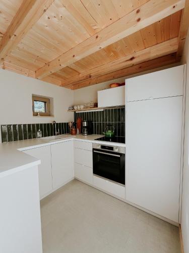 a kitchen with white cabinets and a wooden ceiling at Grange ALMA in Obernai