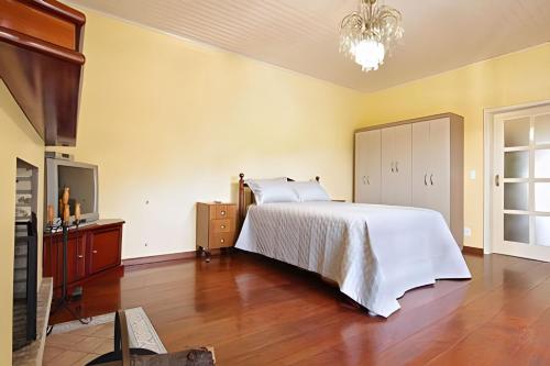 ein Schlafzimmer mit einem großen weißen Bett und Holzböden in der Unterkunft Rosa Casa Dália in Gramado