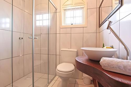 ein Badezimmer mit Toilette und Waschbecken in der Unterkunft Rosa Casa Dália in Gramado