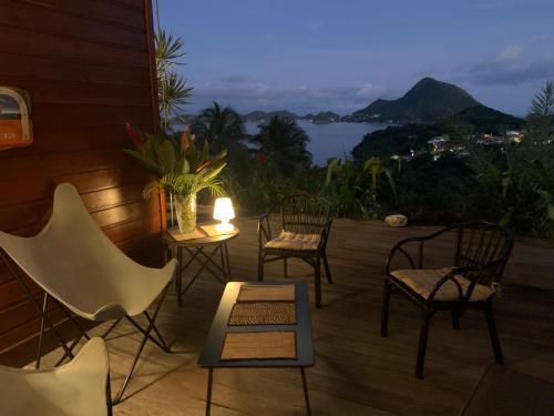 a deck with chairs and a table and a view of the water at villa Kabri terre de bas in Terre-de-Bas