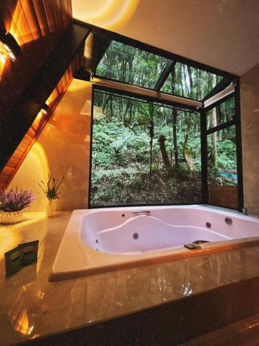 a bath tub in a bathroom with a large window at Rosa Cabana de Canela in Canela