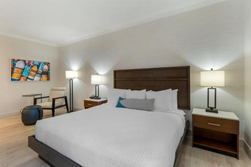 a bedroom with a bed and two lamps and a chair at Best Western Plus All Suites Inn in Santa Cruz