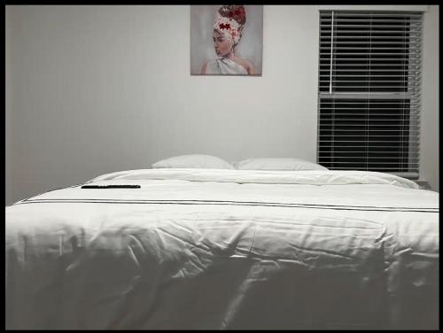 a white bed in a bedroom with a picture on the wall at Banty Villa - Guest Room A in Austin