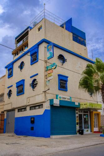 a building with blue doors and windows on a street at Dinosaur Anza Surf House in Agadir
