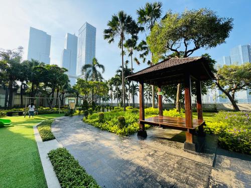 a bench in a park with buildings in the background at Stunning Comfy 2BR Apartment at the Heart of Jakarta in Jakarta