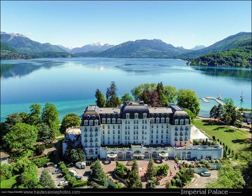 - une vue aérienne sur un bâtiment situé sur un lac dans l'établissement Reflet Bleu du Lac d'Annecy 3 étoiles - Face au lac, Parking gratuit, Paddle board, à Doussard