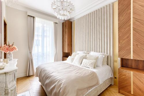 une chambre avec un grand lit blanc avec un lustre dans l'établissement Artistic Luxury 3-Bedroom Apartment - Champs-Élysées, à Paris