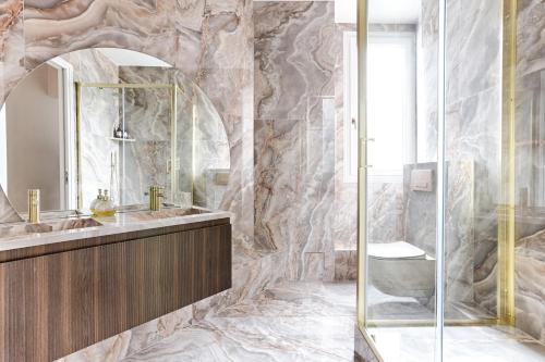 une salle de bain avec un lavabo et une douche en verre dans l'établissement Artistic Luxury 3-Bedroom Apartment - Champs-Élysées, à Paris