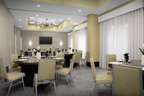 a dining room with tables and chairs and a tv at Hilton Garden Inn Jacksonville Downtown Southbank in Jacksonville