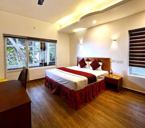 a bedroom with a large bed and two windows at White Shell Beach House in Kannur