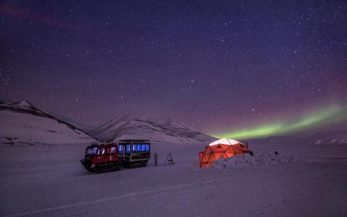 a tent and two trucks in the snow at night at Radisson Blu Polar Hotel, Spitsbergen in Longyearbyen