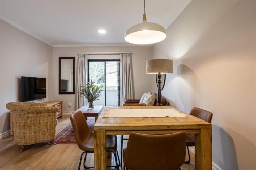 a dining room and living room with a table and chairs at Vino Self Catering Apartment in Stellenbosch