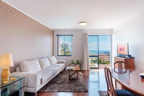a living room with a white couch and a table at Varandas Funchal-Near center in Funchal