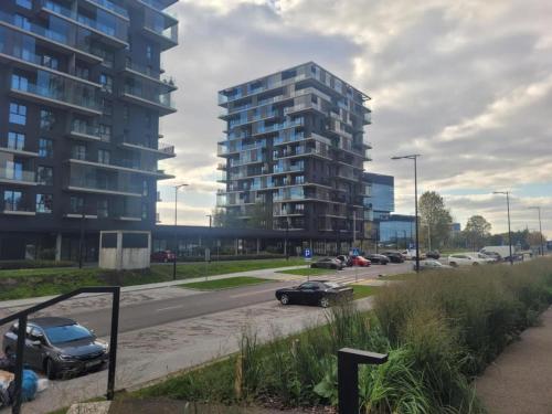 a street with cars parked in front of a tall building at Apartament OneStreet in Katowice