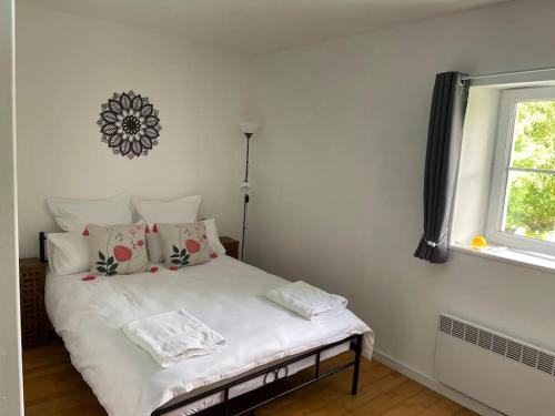 a bedroom with a white bed with pillows and a window at Le Gîte des Jonquilles up to 12 People 6 Bedrooms in Melleran