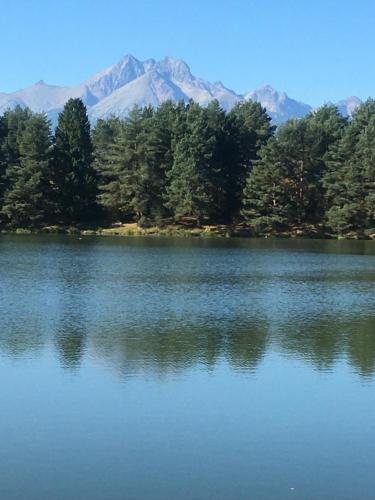 a large lake with trees and mountains in the background at Tatraview House in Veľká Lomnica