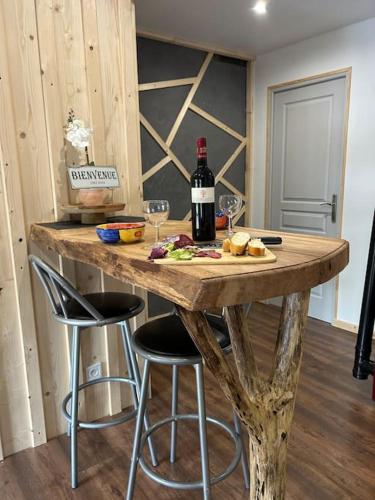 - une table en bois avec une bouteille de vin et deux tabourets de bar dans l'établissement Studio cosy ambiance vosgienne à 20 mn de Gerardmer, à Lépanges-sur-Vologne