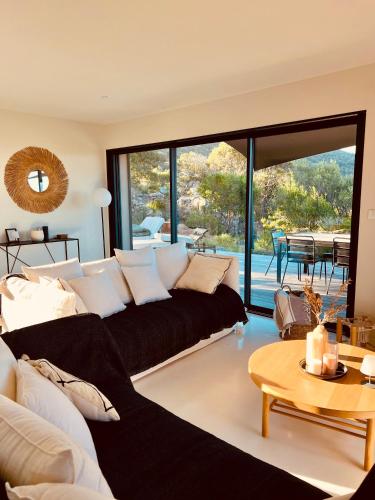 a living room with a black couch and a table at Villa architecte vue mer et maquis in Figari