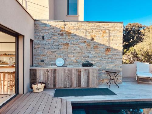 a patio with a table and a brick wall at Villa architecte vue mer et maquis in Figari