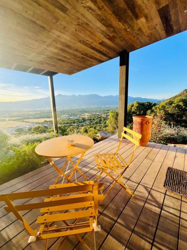 a table and chairs on a deck with a view at Villa architecte vue mer et maquis in Figari