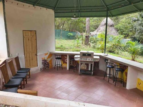 a patio with a table and chairs under a green umbrella at Cabañas Los Jobos in Villarreal